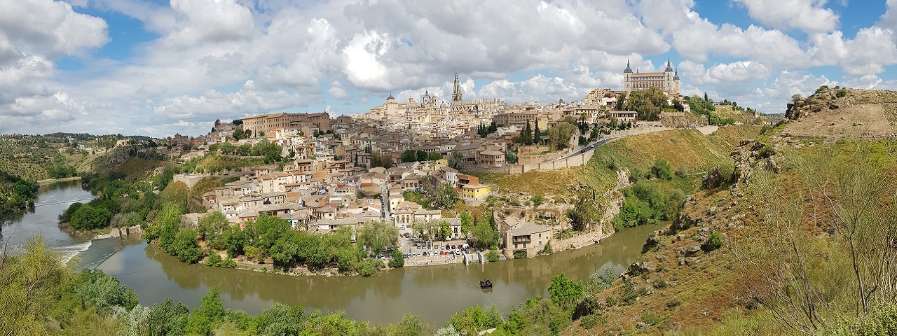 Foto lejana de la vista de un pueblo en lo alto de un cerro rodeado por un río