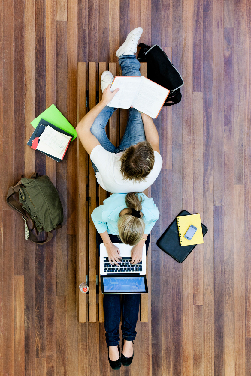 Estudiantes trabajando sobre el suelo, apoyando sus espaldas