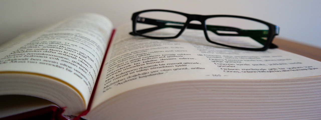 libro abierto a modo de lectura - gafas negras encima del libro
