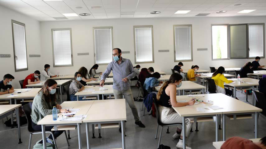 Un aula con estudiantes y un profesor, todos con mascarillas