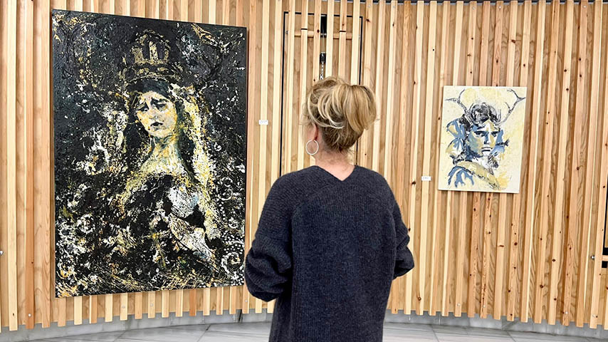 Una mujer contempla la exposición de pinturas de Adela Camacho