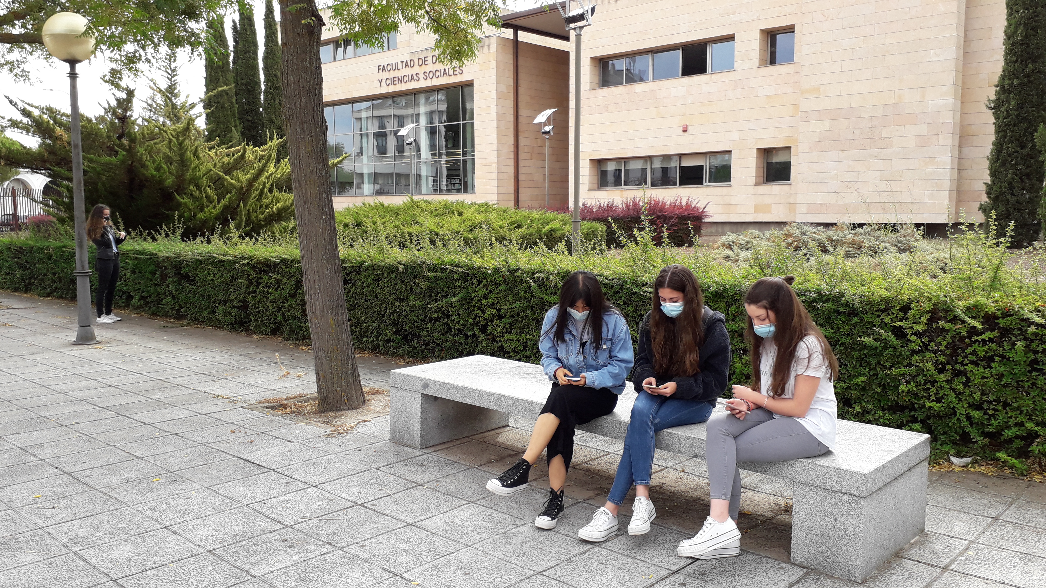 Tres alumnas miran sus móviles en el Campus de Ciudad Real